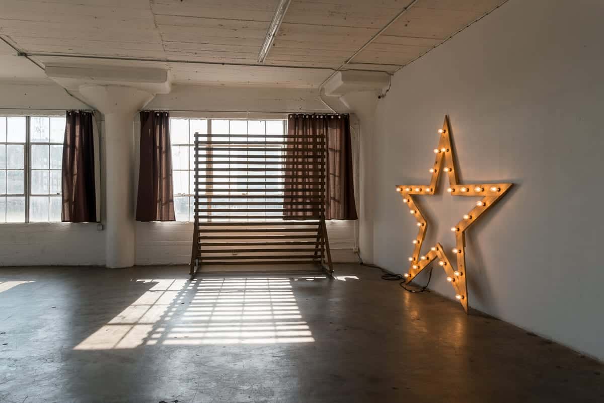 Stage with a wooden corner, large blinds and a marquee star available for rental in Los Angeles