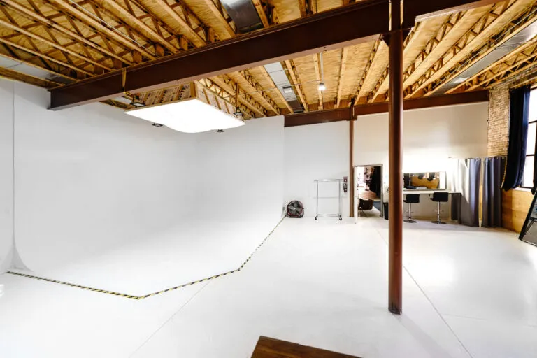 Large daylight photo studio with cyc-wall, tall windows, grand piano, and wooden platform near you Chicago 2